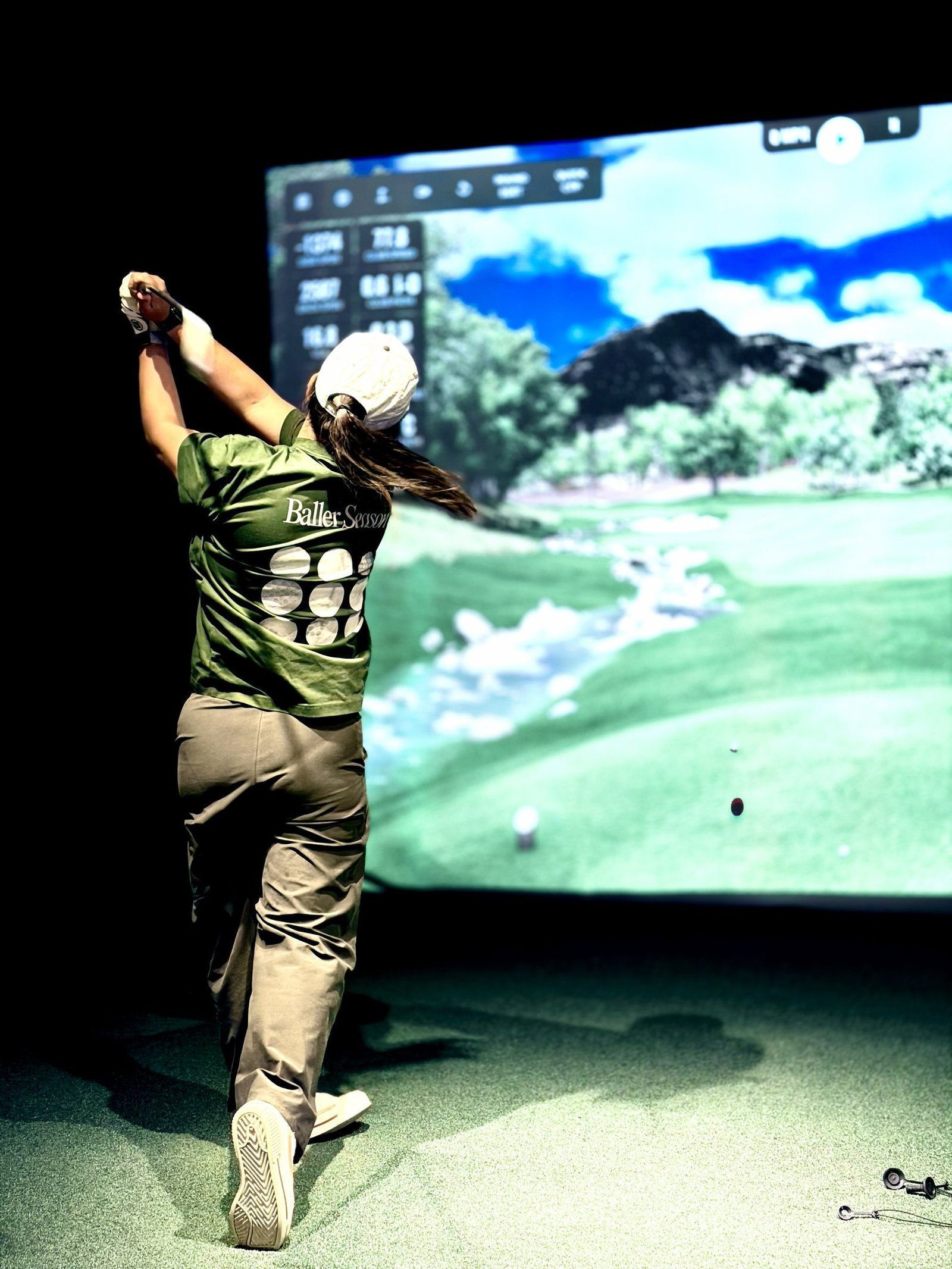 Golfer mid-swing in a Birdie Central simulator bay