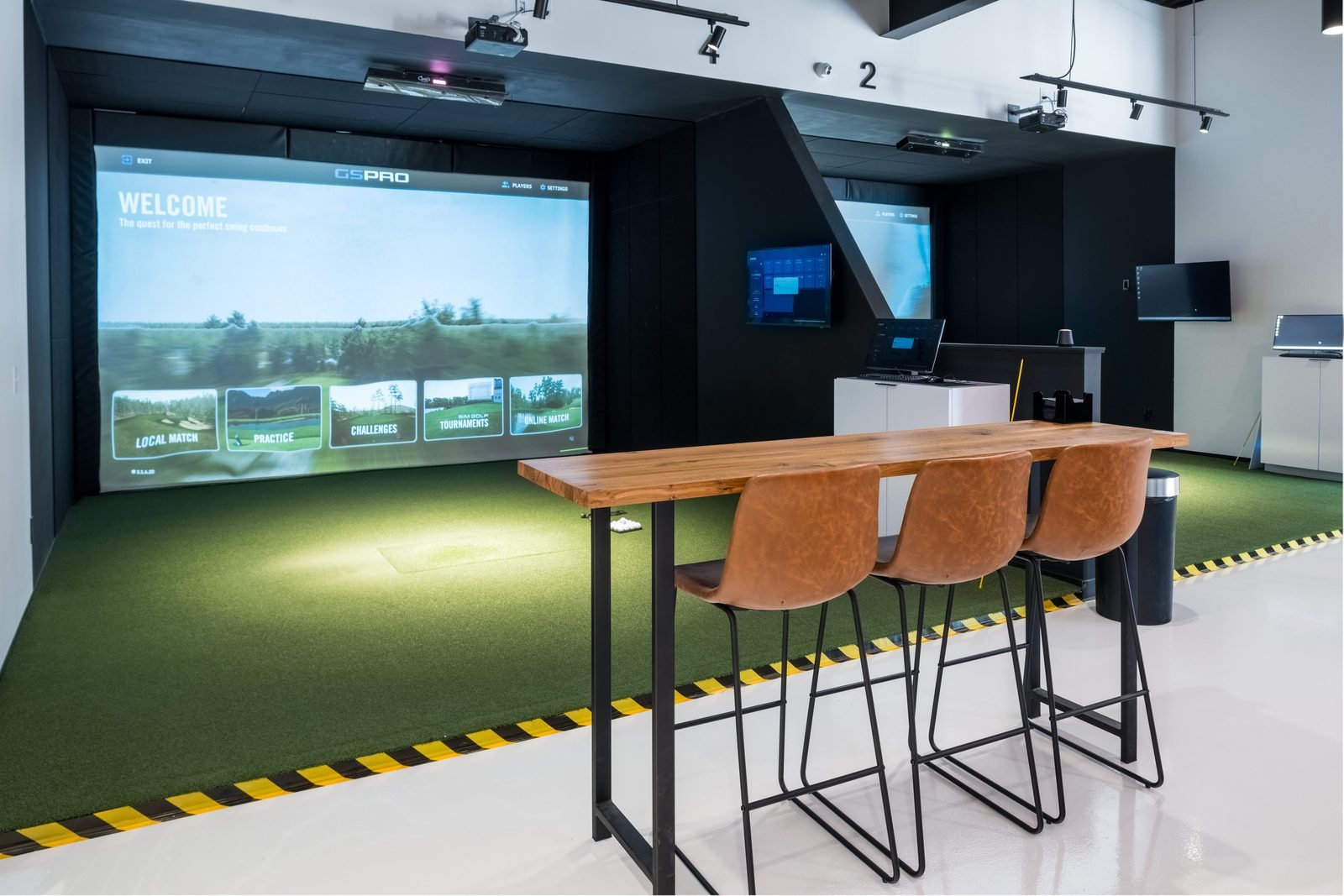 Open simulator bay with high-top seating at Birdie Central