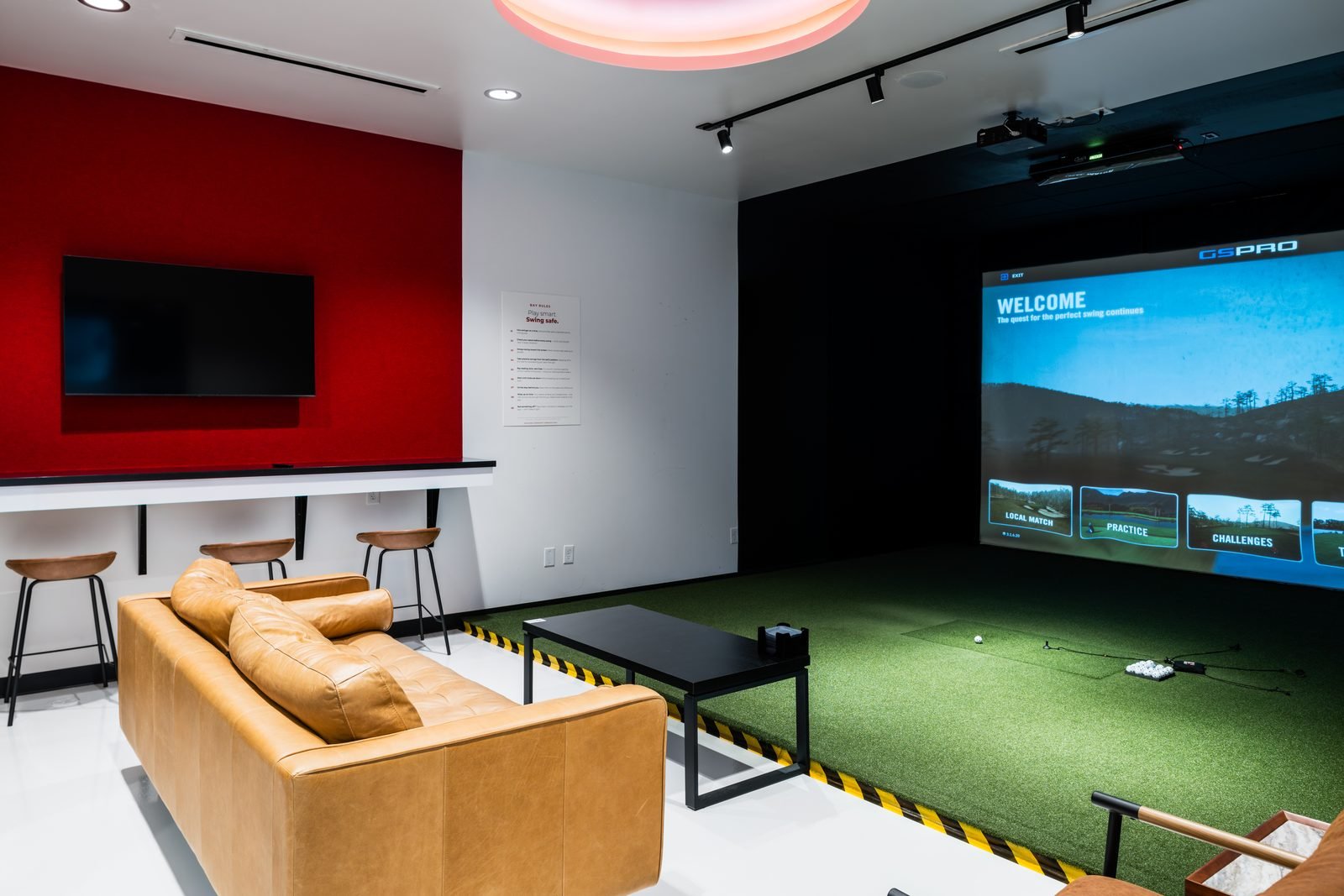 Private simulator bay with leather sofa and lounge seating at Birdie Central