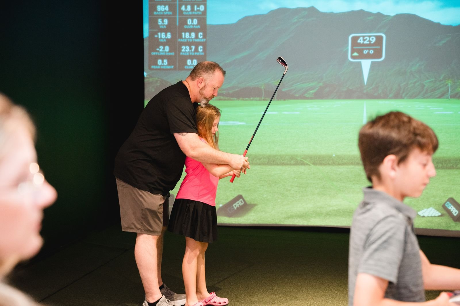 A parent helping a child with her grip on a simulator